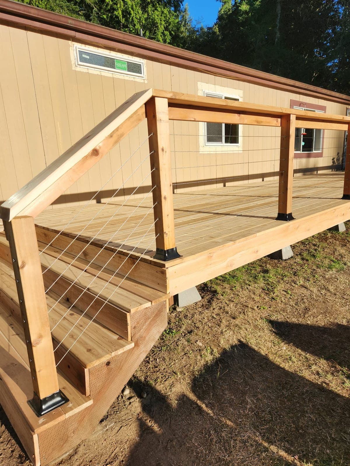 Cedar deck with stainless cable railing and steps, attached to a home with tan siding
