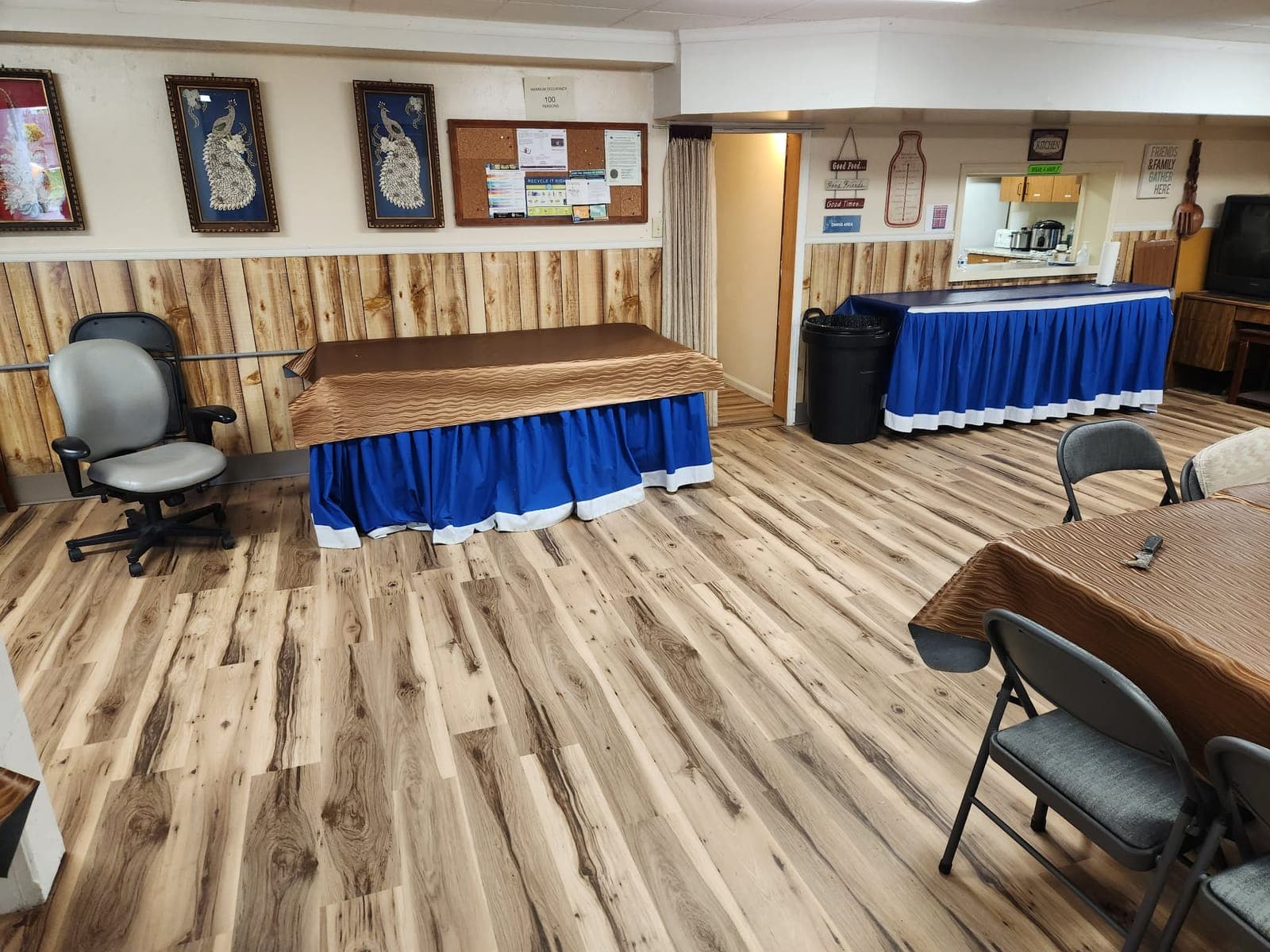 Large common room with new wood-look plank flooring and wood wainscot paneling along the walls